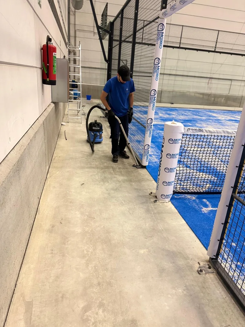 Operario aspirando la zona de paso junto a una pista de pádel cubierta